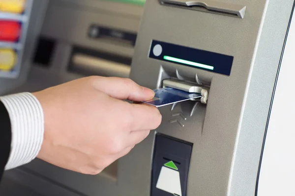 Man putting debit card into ATM machine